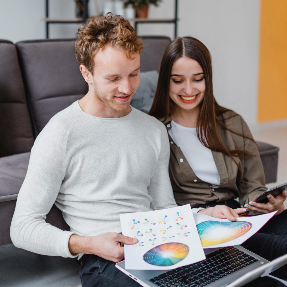 Happy couple sitting on a couch reviewing investment and insurance documents at home