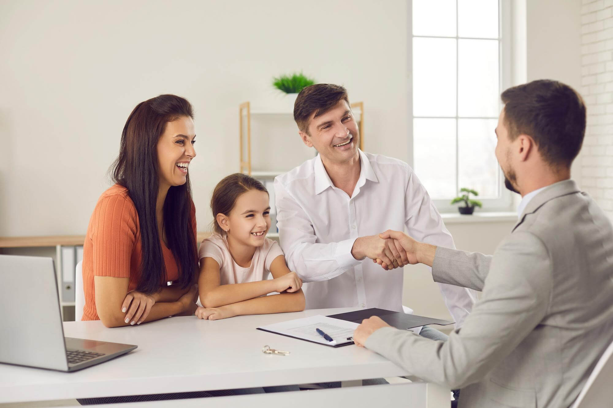 A cheerful family discussing life insurance options with an advisor across a desk, showcasing trust and security in financial planning.