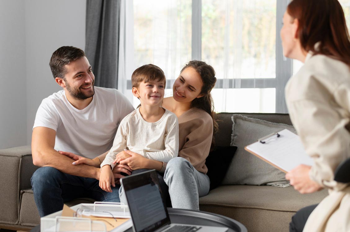 Young couple with child smiling during life insurance consultation at home with advisor and laptop